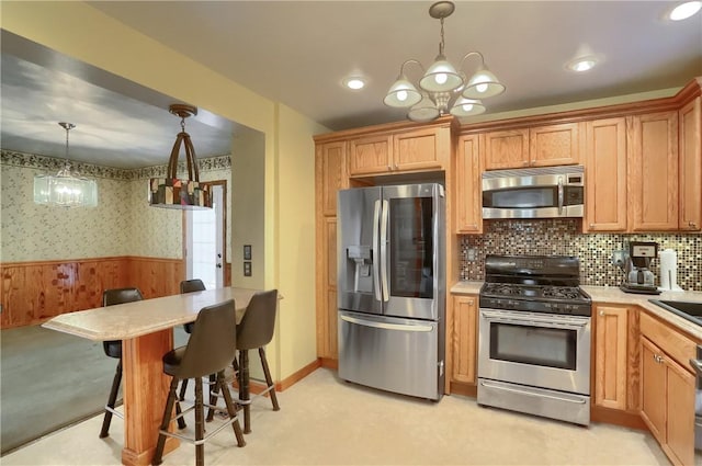 kitchen featuring pendant lighting, a notable chandelier, stainless steel appliances, and a breakfast bar