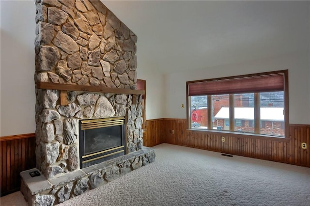 carpeted living room featuring a fireplace and wooden walls