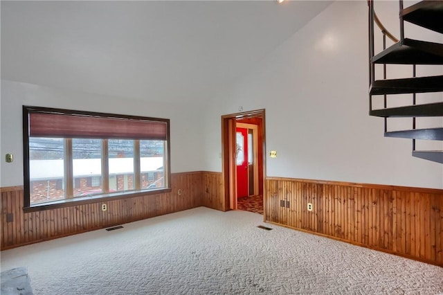 spare room with light carpet, wooden walls, and lofted ceiling