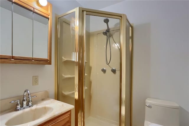 bathroom featuring vanity, a shower with door, and toilet