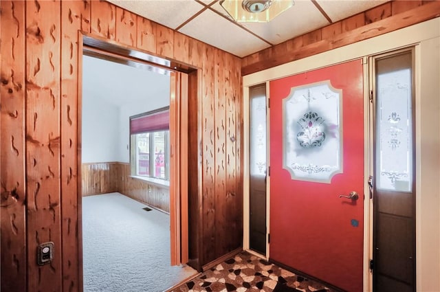 carpeted entryway featuring wood walls