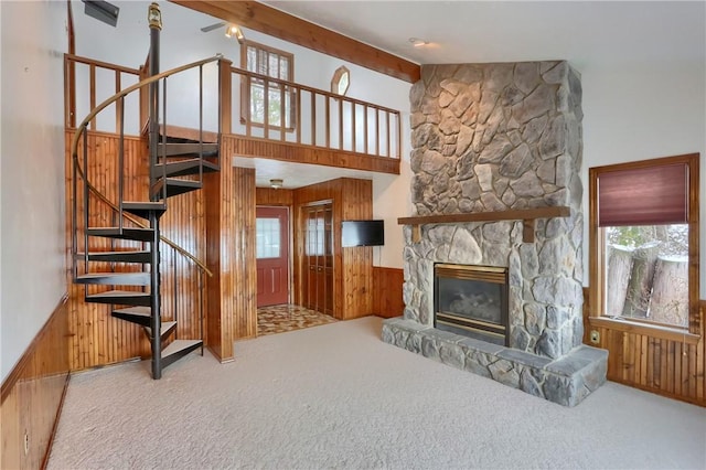 living room featuring a fireplace, wooden walls, plenty of natural light, and carpet flooring