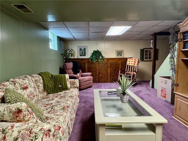 living room with a paneled ceiling, carpet floors, and wooden walls