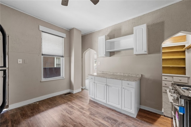 kitchen with light hardwood / wood-style flooring, white cabinetry, ceiling fan, and stainless steel range with gas stovetop