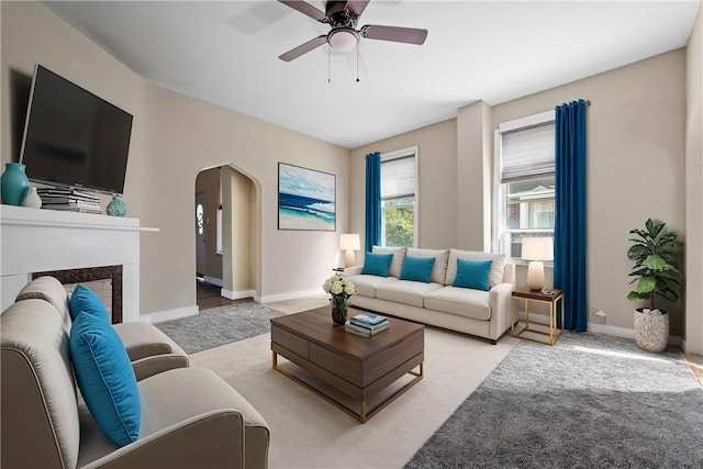 carpeted living room with a fireplace and ceiling fan