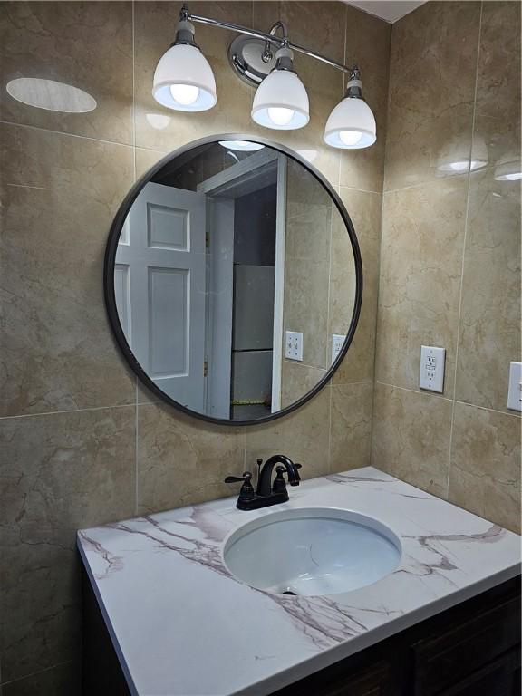 bathroom with vanity and tile walls