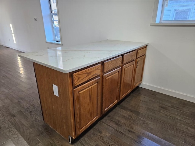 kitchen featuring kitchen peninsula, light stone countertops, and dark wood-type flooring