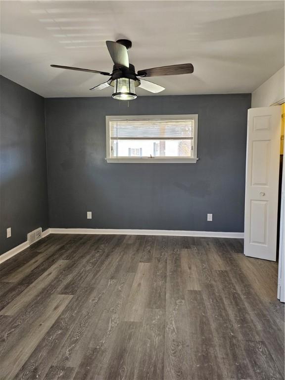 spare room with dark hardwood / wood-style flooring and ceiling fan