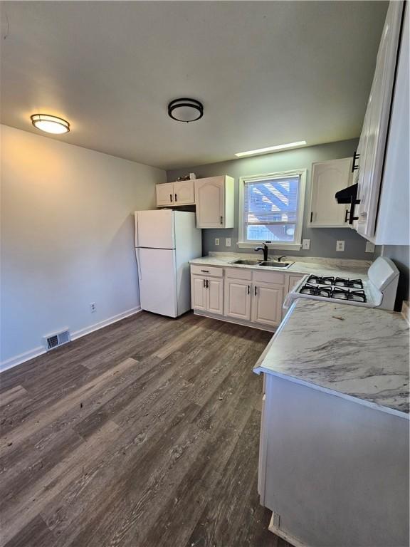 kitchen featuring dark hardwood / wood-style flooring, white appliances, white cabinetry, and sink