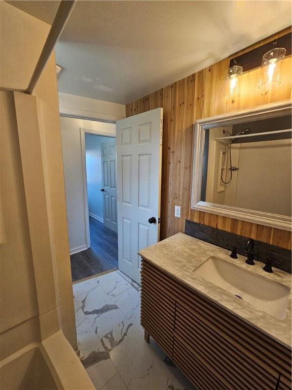 bathroom with vanity, wood walls, and walk in shower