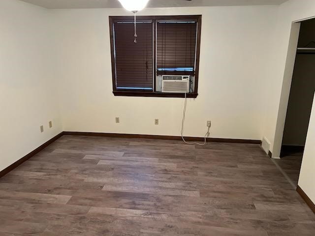 unfurnished bedroom featuring cooling unit and dark hardwood / wood-style floors