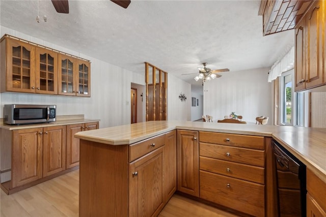 kitchen featuring kitchen peninsula, a textured ceiling, black dishwasher, and light hardwood / wood-style flooring