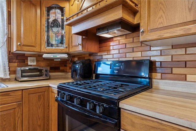 kitchen with decorative backsplash, black gas range, and custom exhaust hood