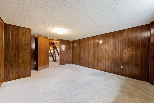 empty room featuring wood walls and a textured ceiling