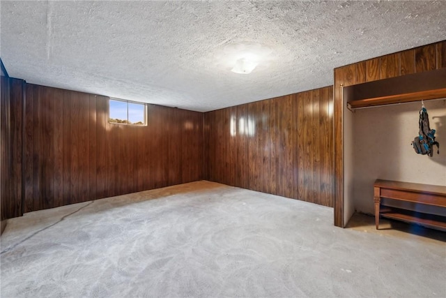 basement with light carpet, a textured ceiling, and wood walls