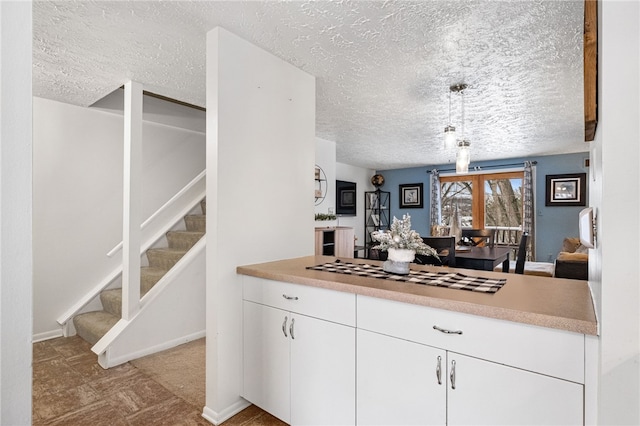 kitchen with white cabinets, pendant lighting, and a textured ceiling