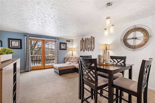 dining area featuring light carpet, french doors, and a textured ceiling