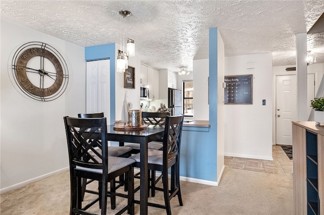 dining area with light colored carpet and a textured ceiling