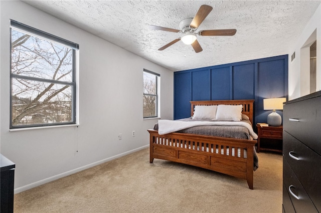 bedroom with a textured ceiling, light colored carpet, and ceiling fan