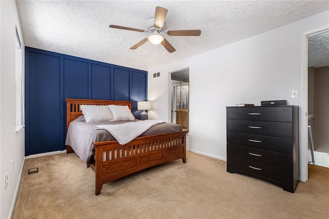 bedroom featuring a textured ceiling, light colored carpet, and ceiling fan