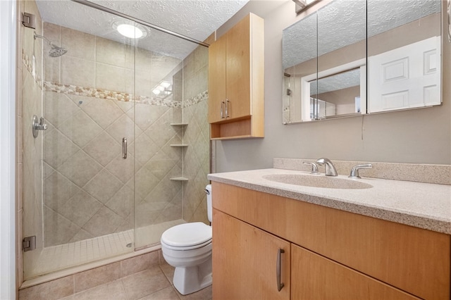 bathroom featuring tile patterned flooring, a textured ceiling, toilet, vanity, and a shower with shower door