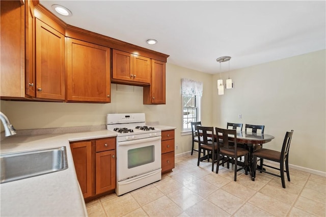 kitchen with decorative light fixtures, white range with gas cooktop, and sink