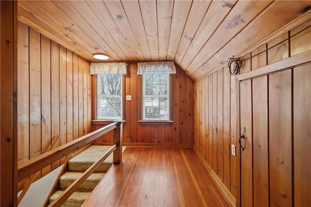 additional living space with wood walls, wood ceiling, vaulted ceiling, and wood-type flooring