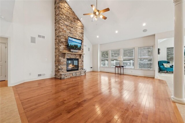 unfurnished living room featuring ornate columns, high vaulted ceiling, light hardwood / wood-style flooring, ceiling fan, and a fireplace