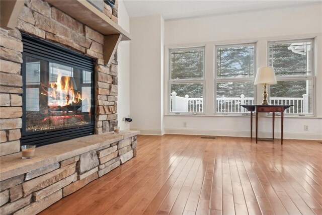 living room featuring a stone fireplace and light wood-type flooring