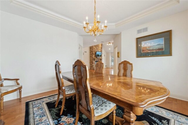 dining area featuring ornamental molding, hardwood / wood-style floors, a fireplace, and a tray ceiling