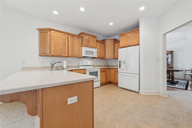 kitchen with a kitchen breakfast bar, sink, white appliances, and kitchen peninsula