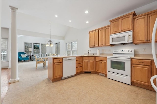 kitchen featuring ornate columns, vaulted ceiling, decorative light fixtures, sink, and white appliances