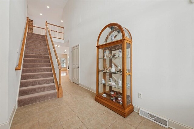 stairway featuring a towering ceiling and tile patterned floors