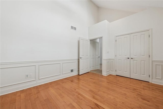 unfurnished bedroom with vaulted ceiling, light wood-type flooring, and a closet