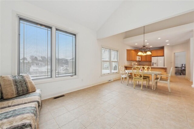 dining space with light tile patterned floors, high vaulted ceiling, and a chandelier