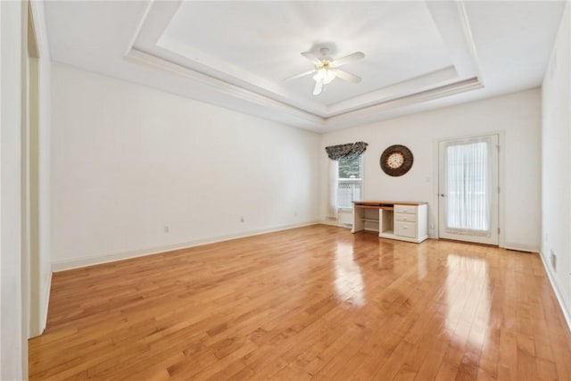 unfurnished living room with hardwood / wood-style flooring, built in desk, a raised ceiling, and ceiling fan