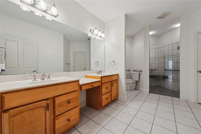 bathroom with tile patterned flooring, vanity, a tile shower, and toilet