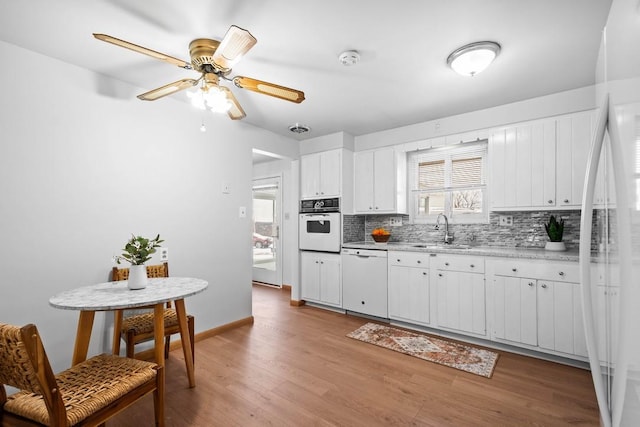 kitchen featuring backsplash, white appliances, sink, light hardwood / wood-style flooring, and white cabinets