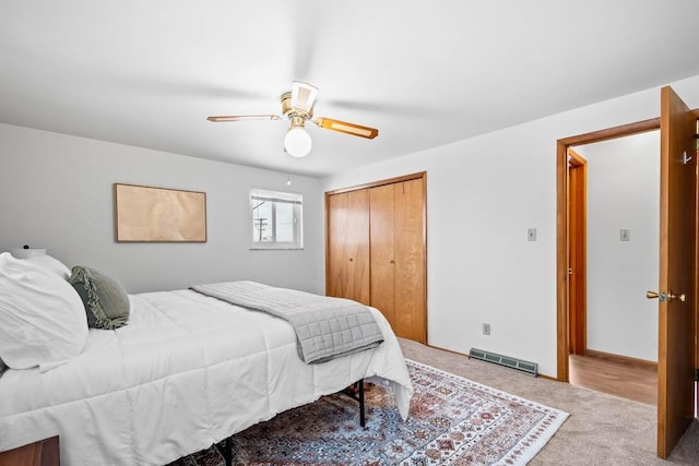 bedroom with ceiling fan, light colored carpet, and a closet