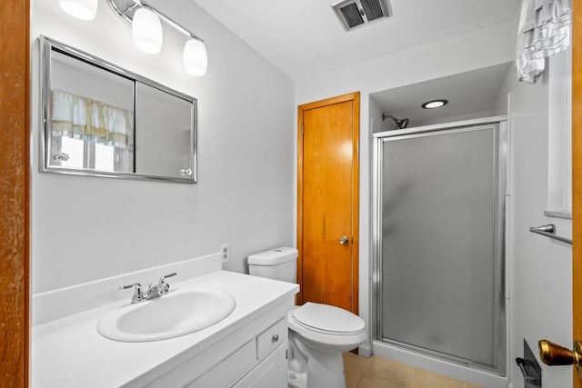 bathroom with tile patterned floors, a shower with door, vanity, and toilet