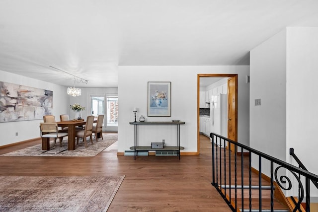 interior space featuring rail lighting, dark wood-type flooring, and a notable chandelier