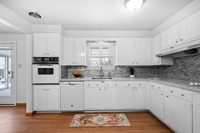 kitchen featuring tasteful backsplash, white cabinetry, sink, and white appliances