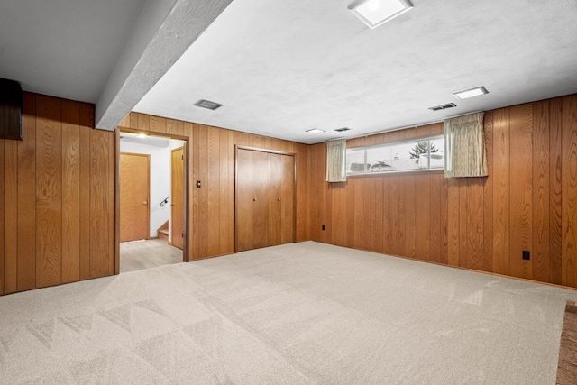 spare room featuring beam ceiling, wood walls, and light colored carpet