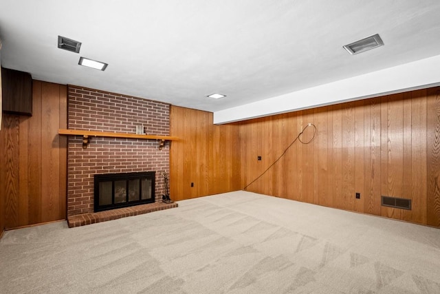 unfurnished living room with carpet flooring, wooden walls, and a brick fireplace