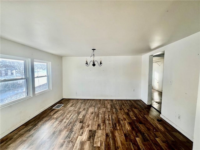 unfurnished dining area with dark hardwood / wood-style floors and an inviting chandelier