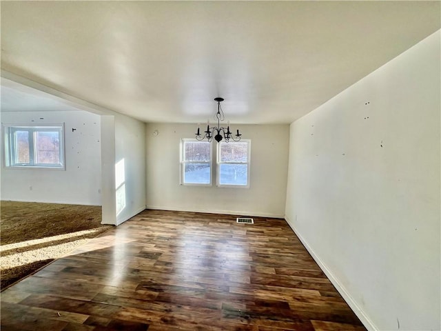 unfurnished dining area featuring dark hardwood / wood-style flooring and an inviting chandelier