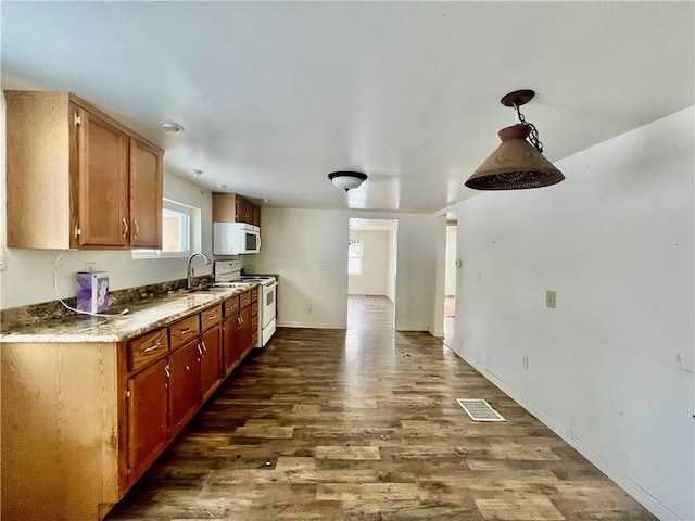 kitchen with dark hardwood / wood-style flooring, white appliances, decorative light fixtures, and sink