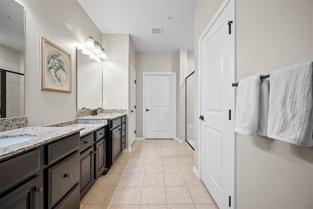 bathroom with tile patterned floors, a shower with door, and vanity