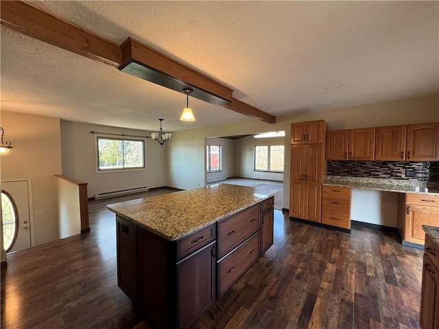 kitchen featuring backsplash, a baseboard radiator, a chandelier, a center island, and plenty of natural light