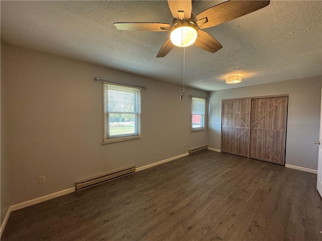 unfurnished bedroom with a textured ceiling, ceiling fan, dark wood-type flooring, and a baseboard heating unit